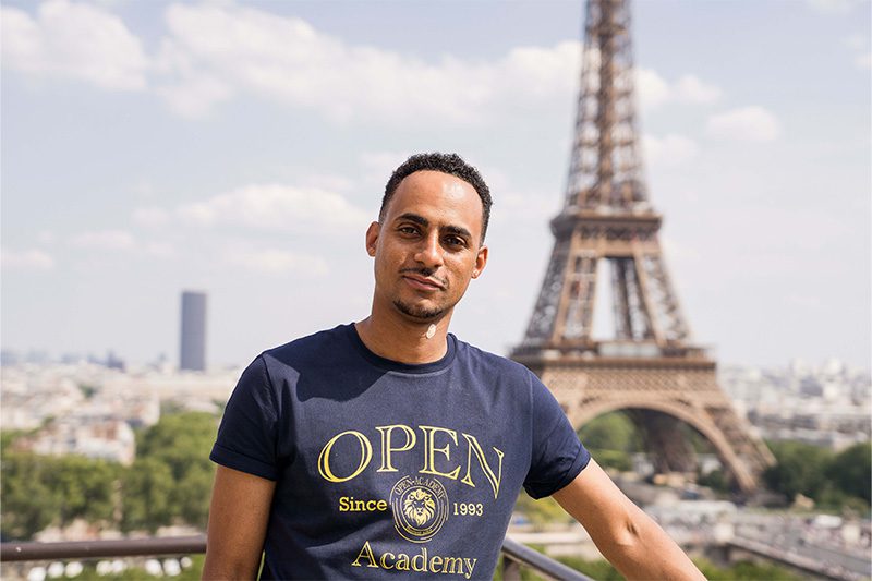 Un homme pose devant la majestueuse tour Eiffel.